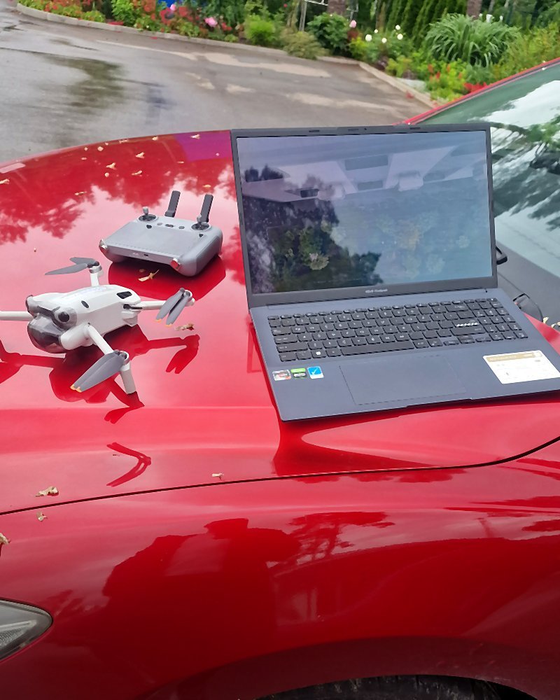 Dronas ir kompiuteris ant automobilio kapoto